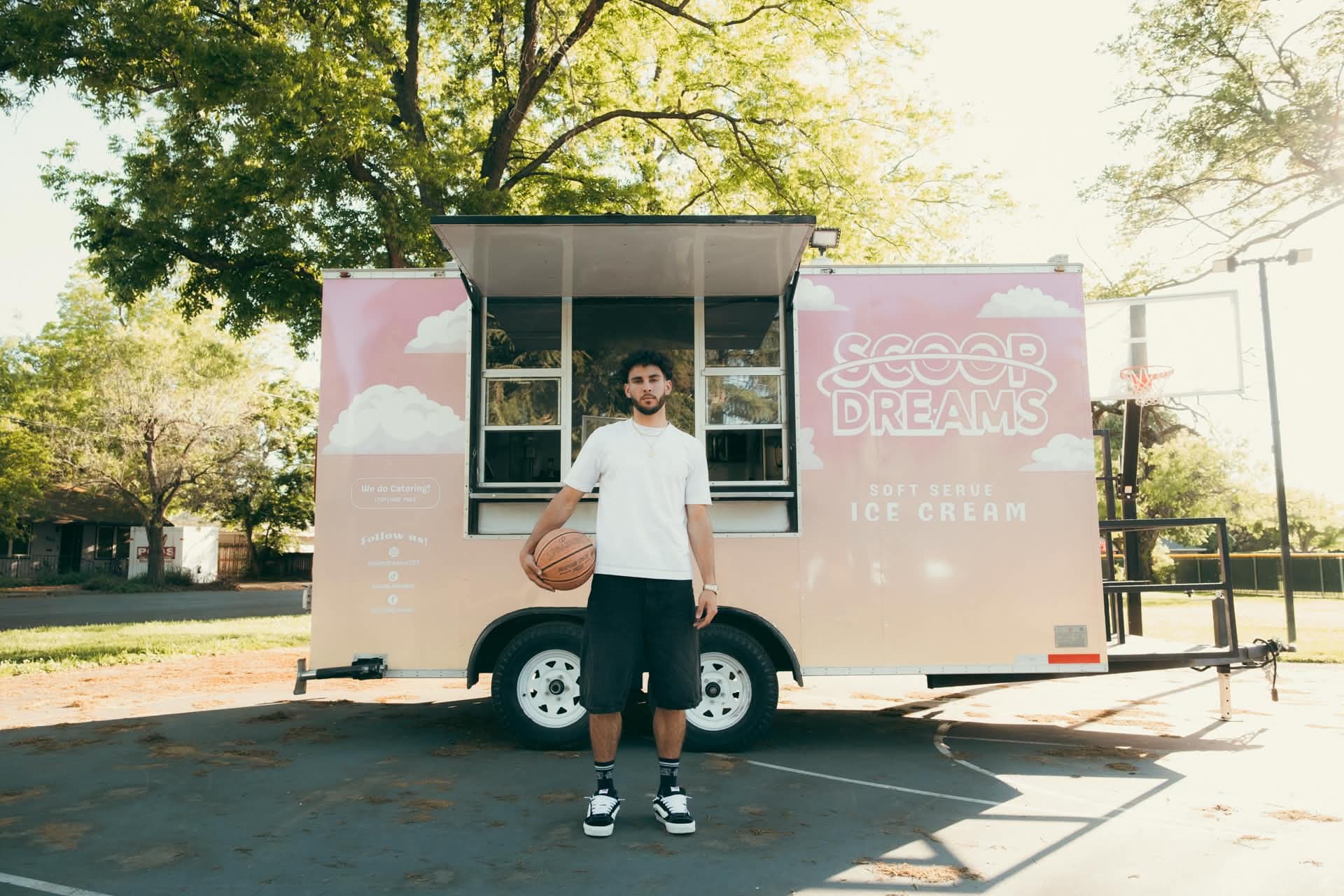 Devan Minouei in a Scoop Dreams jersey holding a basketball and a vanilla cone in a Solano County field