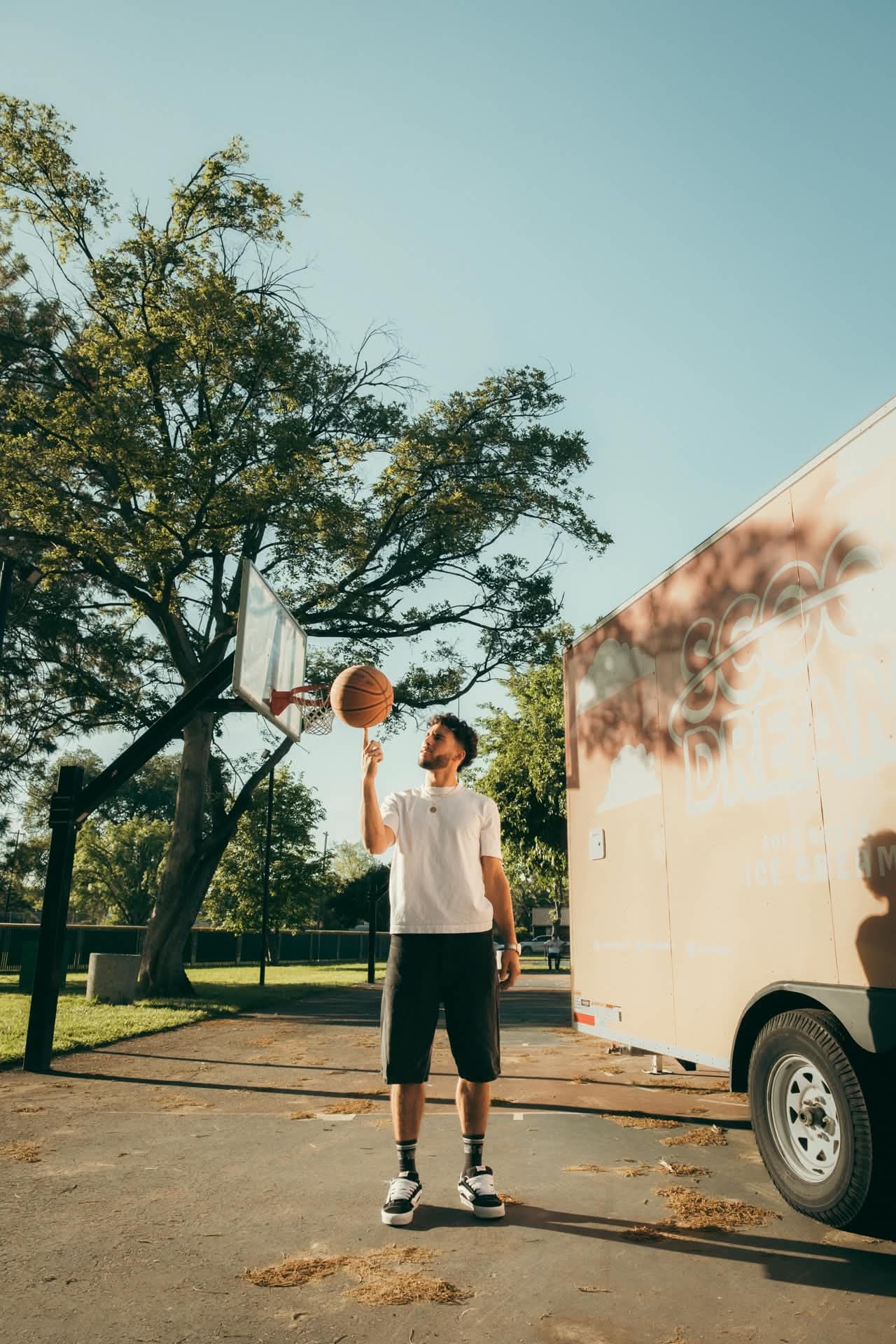 Devan Minouei spinning a basketball on his finger next to the Scoop Dreams trailer