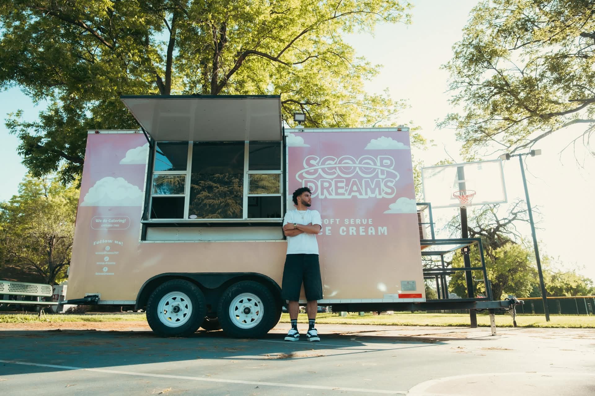 Founder Devan Minouei standing in front of the Scoop Dreams trailer at a Vacaville basketball court